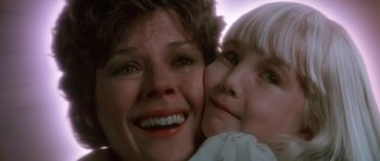 Movie still from “Poltergeist II: The Other Side” (1986), directed by Brian Gibson – A person and a child smiling; Close Up shot, Low angle