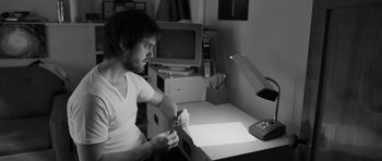 Movie still from “Polytechnique” (2009), directed by Denis Villeneuve – A man sitting at a desk in front of a computer; Medium shot, High angle