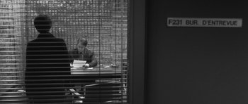 Movie still from “Polytechnique” (2009), directed by Denis Villeneuve – A man sitting at a table with papers in front of him; Wide shot, Over the shoulder angle