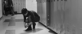 Movie still from “Polytechnique” (2009), directed by Denis Villeneuve – A woman tying her shoes in front of lockers; Wide shot, Low angle