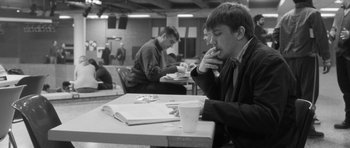 Movie still from “Polytechnique” (2009), directed by Denis Villeneuve – A man sitting at a table eating a sandwich; Close Up shot, High angle