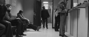 Movie still from “Polytechnique” (2009), directed by Denis Villeneuve – A man walking down a hallway in a building; Wide shot, High angle