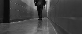 Movie still from “Polytechnique” (2009), directed by Denis Villeneuve – A person walking down a hallway in a building; Wide shot, Low angle