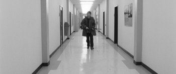 Movie still from “Polytechnique” (2009), directed by Denis Villeneuve – A man in a coat is walking down a hallway; Wide shot, High angle