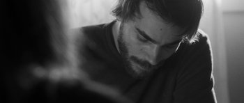 Movie still from “Polytechnique” (2009), directed by Denis Villeneuve – Black and white photograph of a bearded man looking down; Close Up shot, High angle