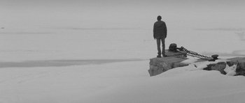 Movie still from “Polytechnique” (2009), directed by Denis Villeneuve – A man standing on top of a cliff in the snow; Wide shot, High angle