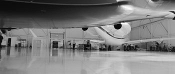 Movie still from “Polytechnique” (2009), directed by Denis Villeneuve – People are standing in an airport waiting for their luggage; Extreme Wide shot, Low angle