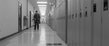 Movie still from “Polytechnique” (2009), directed by Denis Villeneuve – A man walking down a hallway in a school; Wide shot, High angle