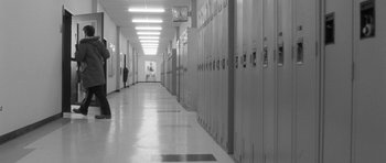 Movie still from “Polytechnique” (2009), directed by Denis Villeneuve – A person walking down a hallway in a building; Wide shot, High angle