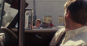 Movie still from “Porky's” (1981), directed by Bob Clark – A man driving a car with a man sitting in the passenger's seat; Close Up shot, Over the shoulder angle