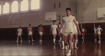 Movie still from “Porky's” (1981), directed by Bob Clark – A group of young men standing on a basketball court; Wide shot, Low angle