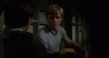 Movie still from “Porky's” (1981), directed by Bob Clark – A man in a striped t - shirt is looking at the camera; Close Up shot, Over the shoulder angle