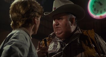 Movie still from “Porky's” (1981), directed by Bob Clark – A man in a cowboy hat talking to another man in a cowboy hat; Close Up shot, Over the shoulder angle