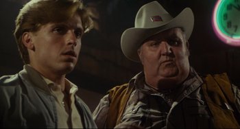 Movie still from “Porky's” (1981), directed by Bob Clark – A man in a cowboy hat standing next to another man; Close Up shot, Over the shoulder angle
