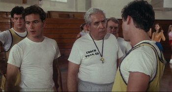 Movie still from “Porky's” (1981), directed by Bob Clark – An older man in a white shirt is talking to a group of young men; Medium shot, Over the shoulder angle