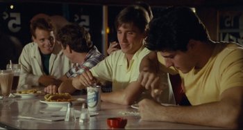 Movie still from “Porky's” (1981), directed by Bob Clark – A group of people sitting at a table eating pizza; Medium shot, Over the shoulder angle
