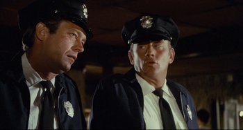 Movie still from “Porky's” (1981), directed by Bob Clark – Two police officers standing next to each other; Close Up shot, Low angle
