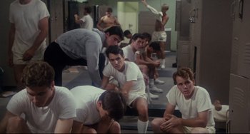 Movie still from “Porky's” (1981), directed by Bob Clark – A group of young men sitting on the ground; Wide shot, High angle