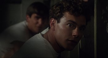 Movie still from “Porky's” (1981), directed by Bob Clark – A man in a white t - shirt is looking at the camera; Close Up shot, Low angle