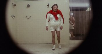 Movie still from “Porky's” (1981), directed by Bob Clark – A man in white shorts and a red scarf standing in a bathroom; Wide shot, Low angle