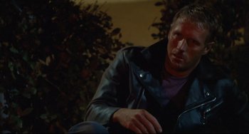 Movie still from “Porky's” (1981), directed by Bob Clark – A man sitting on the ground wearing a leather jacket; Close Up shot, Low angle