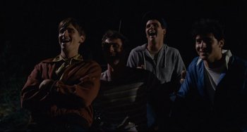 Movie still from “Porky's” (1981), directed by Bob Clark – A group of men standing next to each other in the dark; Medium shot, Over the shoulder angle