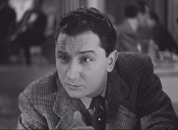 Movie still from “Port of Shadows” (1938), directed by Marcel Carné – An old photo of a man in a suit and tie; Close Up shot, Low angle