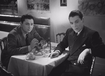Movie still from “Port of Shadows” (1938), directed by Marcel Carné – Two young men sitting at a table in a restaurant; Medium shot, High angle