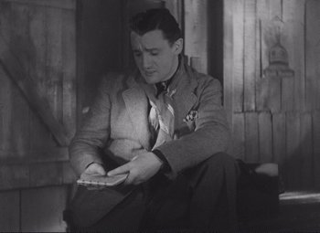 Movie still from “Port of Shadows” (1938), directed by Marcel Carné – A black and white photo of a man writing on a piece of paper; Medium shot, High angle