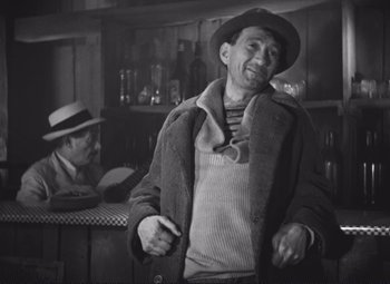 Movie still from “Port of Shadows” (1938), directed by Marcel Carné – An older man wearing a hat and a jacket; Medium shot, Low angle