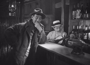 Two men are standing at a bar and one of them is smoking a cigarette