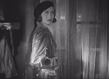 Movie still from “Port of Shadows” (1938), directed by Marcel Carné – A black and white photo of a woman in a raincoat; Medium shot, Low angle