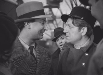 Movie still from “Port of Shadows” (1938), directed by Marcel Carné – Two men in hats and ties talking to each other; Medium shot, Over the shoulder angle