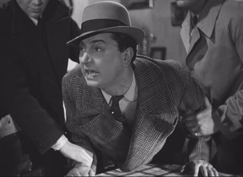 Movie still from “Port of Shadows” (1938), directed by Marcel Carné – An old photo of a man in a hat and a suit; Medium shot, High angle