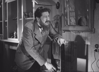 Movie still from “Port of Shadows” (1938), directed by Marcel Carné – An older man leaning against a window sill; Medium shot, Low angle