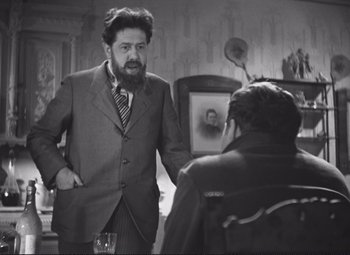 Movie still from “Port of Shadows” (1938), directed by Marcel Carné – An older man wearing a suit talking to a younger man; Medium shot, Over the shoulder angle