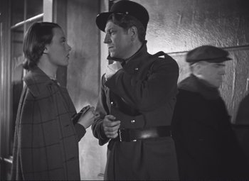 Movie still from “Port of Shadows” (1938), directed by Marcel Carné – An old photo of a man and a young woman; Medium shot, Over the shoulder angle