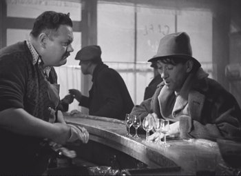 Movie still from “Port of Shadows” (1938), directed by Marcel Carné – Two men at a bar with wine glasses on the counter; Medium shot, Over the shoulder angle