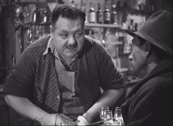 Movie still from “Port of Shadows” (1938), directed by Marcel Carné – Two men sitting at a table in front of drinks; Medium shot, Over the shoulder angle