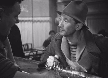 Movie still from “Port of Shadows” (1938), directed by Marcel Carné – An old photo of a man sitting at a bar; Medium shot, Over the shoulder angle