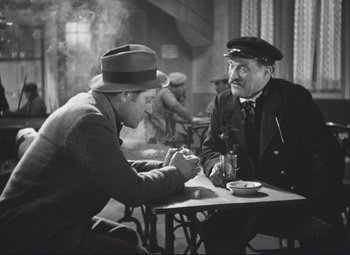 Movie still from “Port of Shadows” (1938), directed by Marcel Carné – Two men sitting at a table in front of each other; Medium shot, High angle