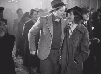 Movie still from “Port of Shadows” (1938), directed by Marcel Carné – A man and a woman standing next to each other; Medium shot, Over the shoulder angle