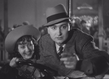 Movie still from “Port of Shadows” (1938), directed by Marcel Carné – A man and a woman are posing for a picture; Medium shot, Low angle