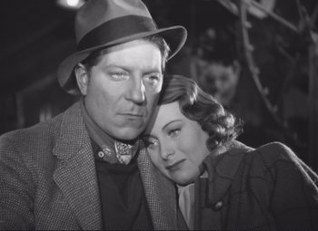 Movie still from “Port of Shadows” (1938), directed by Marcel Carné – An old photo of a man and a woman posing for a picture; Close Up shot, Low angle