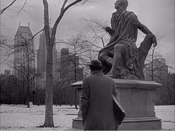 Movie still from “Portrait of Jennie” (1948), directed by William Dieterle – A man standing next to a statue in a park; Wide shot, Low angle