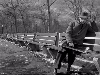 Movie still from “Portrait of Jennie” (1948), directed by William Dieterle – An older man sitting on a bench in a park; Wide shot, High angle