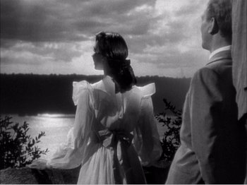 Movie still from “Portrait of Jennie” (1948), directed by William Dieterle – A man and a woman standing next to a body of water; Medium shot, Low angle