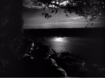 Movie still from “Portrait of Jennie” (1948), directed by William Dieterle – Two people sitting next to each other near a body of water; Extreme Wide shot, High angle