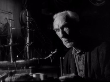 Movie still from “Portrait of Jennie” (1948), directed by William Dieterle – An old man is looking at the camera in a dark room; Close Up shot, Low angle