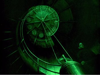 Movie still from “Portrait of Jennie” (1948), directed by William Dieterle – A man standing in front of a clock in a dark room; Wide shot, Overhead angle